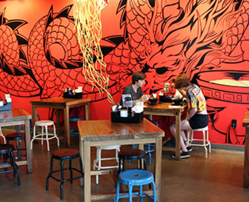 Patrons sit in front of a dragon mural inside Fukuryu Ramen.